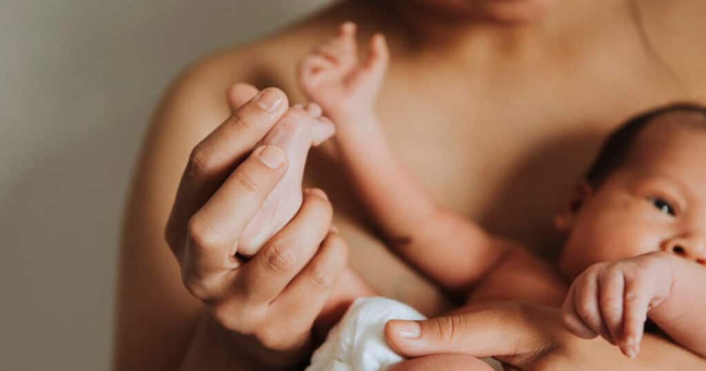 Close-up of a parent gently holding a newborn's tiny hand, symbolizing bonding and care.